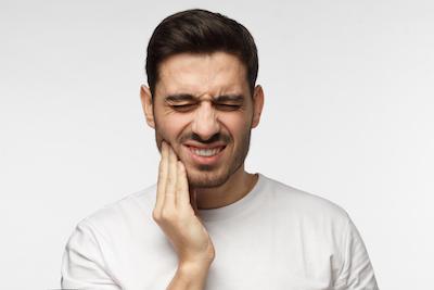 man holding jaw from tooth pain before root canals in arvada, co