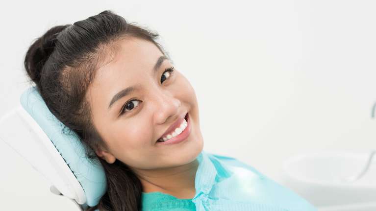 dental crowns arvada | Woman smiling getting a dental exam 