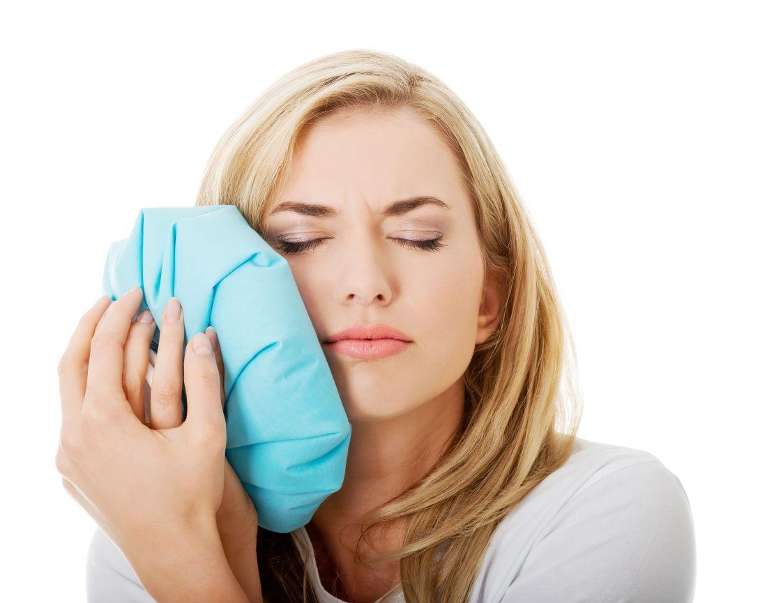 woman holding ice bag on her right cheek